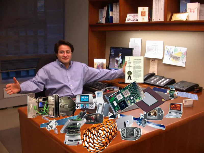 Carlos R. Villamar at his desk surrounded by inventions and patents